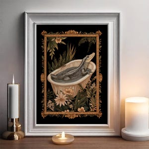 Op de afbeelding: Ingelijste kunstafdruk met een gedetailleerde illustratie van een alligator die ontspant in een vintage badkuip. Het kunstwerk staat tegen een zwarte achtergrond, omgeven door bloemen en botanische elementen in een sierlijke gouden lijst.