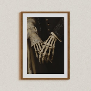 May include: A framed sepia-toned print depicting skeletal hands clasped together. The image highlights the intricate bone structure. The print also shows a person wearing a dark coat and a person wearing a dress with lace sleeves.