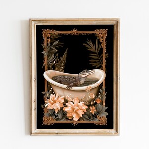 May include: Framed art print depicting an alligator in a vintage bathtub. The artwork has a black background with a gold ornate frame, peach-coloured flowers, and green foliage. The alligator is in the tub with water, creating a whimsical scene.