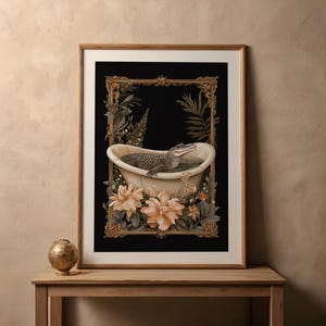 May include: Art print showing an alligator in a bathtub, framed with a gold border and botanical details. The artwork has a black background, with a wooden frame. The image includes flowers and foliage, creating a decorative aesthetic.