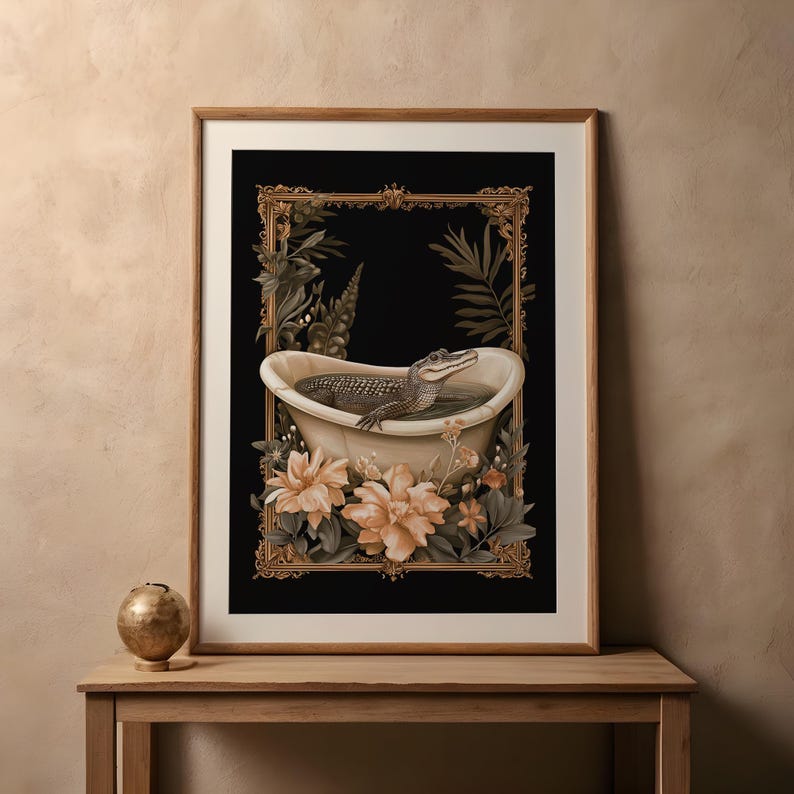 May include: Art print showing an alligator in a bathtub, framed with a gold border and botanical details. The artwork has a black background, with a wooden frame. The image includes flowers and foliage, creating a decorative aesthetic.