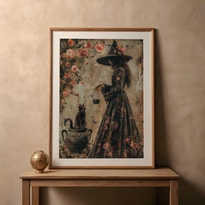 May include: A framed print of a witch in a black dress and a pointed hat, standing with a black cat in a cauldron, surrounded by pink roses.