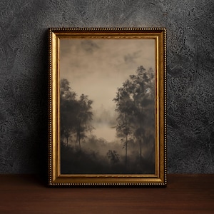 May include: A framed landscape painting with a gold-colored ornate frame. The artwork depicts a misty forest scene with tall, dark trees and a soft, muted color palette. The painting is displayed on a dark wooden surface.