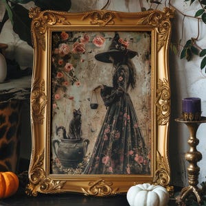 May include: A framed print of a witch in a black dress with floral details, holding a cauldron. A black cat sits in a pot beside her. The frame is ornate and gold.