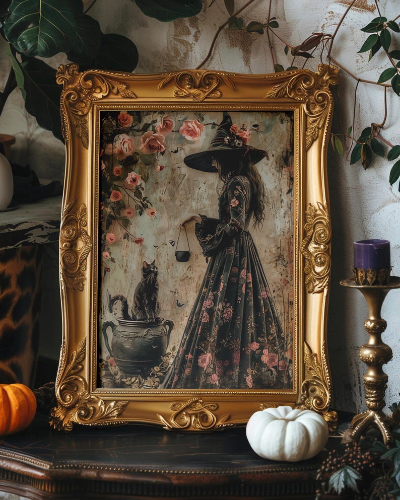May include: A framed print of a witch in a black dress with floral details, holding a cauldron. A black cat sits in a pot beside her. The frame is ornate and gold.