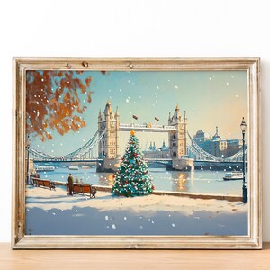 May include: A painting of the Tower Bridge in London with a Christmas tree in the foreground. The bridge is decorated with lights and there is snow falling. The painting is framed in a light wood frame.