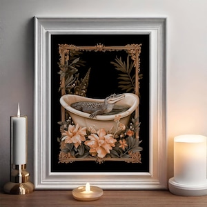 May include: A framed art print depicting an alligator in a bathtub. The artwork has a black background with a gold ornate frame, surrounded by floral and botanical elements. The color palette includes shades of brown, beige, and green.