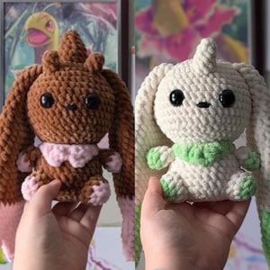 May include: Two handmade crochet bunny plushies. One is brown with pink accents, the other is off-white with green accents. Both have large black eyes and are held up by hands.