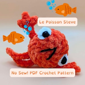 May include: A crocheted orange fish toy named "Le Poisson Steve" with black eyes and a black mouth. The toy is surrounded by blue bubbles and two smaller orange fish toys. The text "No Sew! PDF Crochet Pattern" is below the toy.