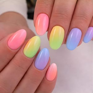 May include: Close-up of a hand with oval-shaped nails painted in a rainbow gradient. The colors transition from pink to yellow, green, and blue, creating a vibrant and eye-catching manicure.