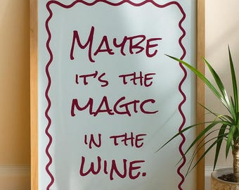 Könnte beinhalten: Gerahmter Kunstdruck mit dem Text "MAYBE IT'S THE MAGIC IN THE WINE" in burgunderfarbener Schrift. Der Text befindet sich innerhalb eines wellenförmigen burgunderfarbenen Randes auf weißem Hintergrund, in einem Naturholzrahmen. Eine Topfpflanze ist sichtbar.