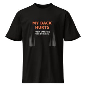 May include: Black t-shirt with the orange text "MY BACK HURTS" above "FROM CARRYING THIS ECONOMY". Two stylized grey trees are below the text. The shirt is made of a soft material.