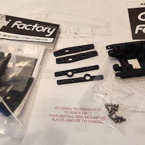 K&ouml;nnte beinhalten: Nahaufnahme eines Sets aus schwarzen Kunststoffteilen f&uuml;r ein 3D-gedrucktes RC-Auto. Die Teile sind mit "Oppai Factory" beschriftet und beinhalten Montageanweisungen. Die Teile umfassen ein Getriebe, seitliche Montageplatten und Schrauben.