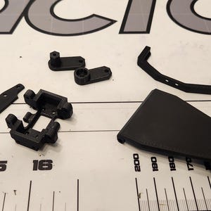 Puede incluir: Surtido de piezas de pl&aacute;stico negro para un coche o robot modelo. Las piezas incluyen un chasis, un parachoques delantero, un parachoques trasero y dos brazos de suspensi&oacute;n.