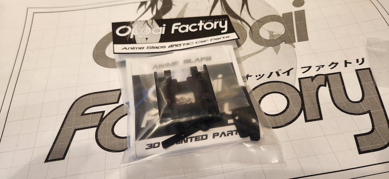 K&ouml;nnte beinhalten: Eine transparente Plastikt&uuml;te mit schwarzen 3D-gedruckten Autoteilen, die mit "Anime Slaps" und "3D Printed Parts" beschriftet sind. Die T&uuml;te ist mit "Oppai Factory Anime Slaps and RC Car Parts" beschriftet.