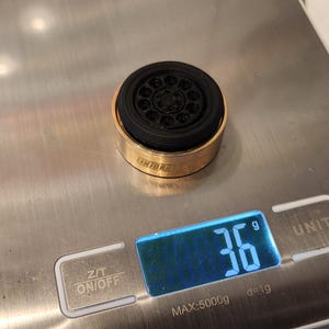 Pu&ograve; includere: Un aeratore per rubinetto in metallo dorato con un inserto in gomma nera, che pesa 36 grammi su una bilancia digitale.