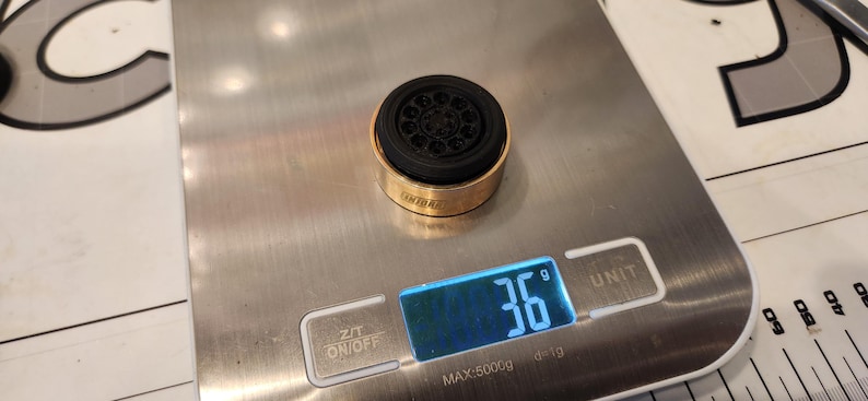 Pu&ograve; includere: Un aeratore per rubinetto in metallo dorato con un inserto in gomma nera, che pesa 36 grammi su una bilancia digitale.