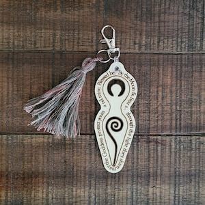 May include: Wooden keychain with a carved image of a goddess symbol and the text "Blessed be. By the Moon & Stars, through the light they shine, may the Goddess protect yours and mine."