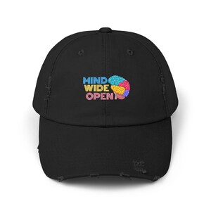 Op de afbeelding: Zwarte distressed baseballcap met de geborduurde tekst "MIND WIDE OPEN" boven een kleurrijke hersenenafbeelding. De cap heeft een gebogen klep en een distressed, versleten uitstraling.