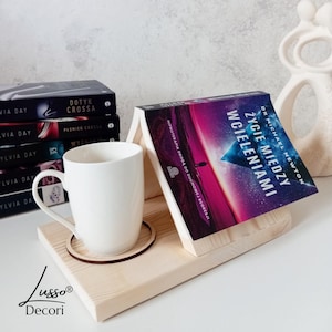 May include: A wooden book stand with a white mug and a book titled "Life Between Lives" by Dr. Michael Newton. The book stand has a cutout for the mug and a small wooden coaster.