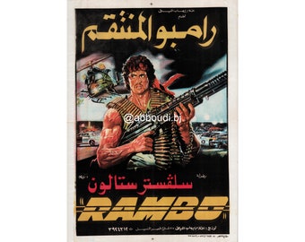 May include: A movie poster for the film "Rambo: The Revenge" featuring Sylvester Stallone as Rambo, holding a machine gun and wearing a red bandana. The poster is in Arabic and features the title "Rambo: The Revenge" in Arabic.
