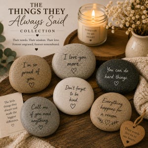 Könnte beinhalten: Eine Sammlung von gravierten Steinen mit inspirierenden Botschaften, darunter "Ich liebe dich mehr" und "Du kannst schwierige Dinge schaffen." Das Bild zeigt auch eine brennende Kerze und ein herzförmiges Holzschild.