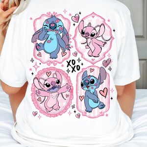 Peut inclure: T-shirt blanc avec quatre motifs de personnages de dessins animés roses et bleus, chacun dans un ovale encadré de rose. Les motifs comprennent des cœurs et le texte "XO XO".
