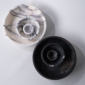 May include: Two sets of nesting bowls, one set is white with black marbling and the other set is black with white marbling.