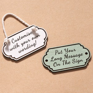 Puede incluir: Dos letreros de madera con un aspecto rústico. El letrero blanco tiene una cuerda atada y dice "Customize with your own wording!" El letrero verde dice "Put Your Long Message On The Sign".