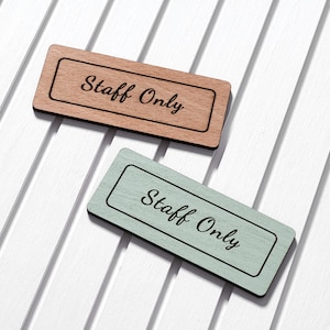 May include: Two wooden signs with the text "Staff Only" in black lettering. One sign is light brown with a dark brown border, and the other is light green with a dark green border.