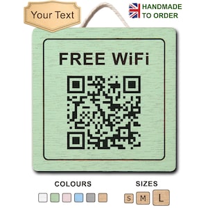 May include: A square light green wooden sign featuring the black text FREE WIFI above a black QR code. The sign has a white rope hanger at the top. Above the sign is a tan label with the text Your Text. To the right is a small British flag icon.