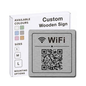 Può includere: Un cartello quadrato in legno grigio con un'icona WiFi nera, il testo WiFi e un codice QR. Dietro, una scatola bianca mostra il testo Custom Wooden Sign, insieme a icone per i colori, le taglie S, M, L e le opzioni di montaggio.
