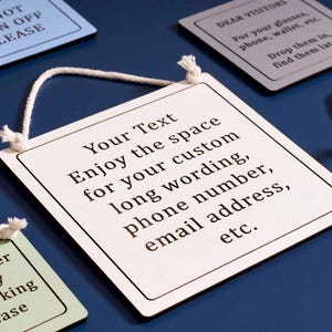 May include: Square, cream-colored signs with black borders and white rope hangers. The signs have various printed messages, including "Your Text" and "Do Not Turn Off Please." The background is a dark blue surface.