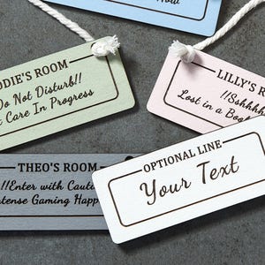 May include: Set of five wooden door hangers in different colours and text. The text on the hangers includes "Jodie's Room", "Lilly's Room", "Theo's Room", and "Optional Line - Your Text".