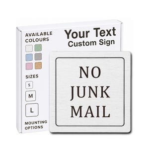 May include: A square white sign with a black border and the black text NO JUNK MAIL. Behind it, a white product box displays the text Your Text Custom Sign, along with a grid of six colour swatches, three size options labelled S, M, and L, and a section for mounting options.