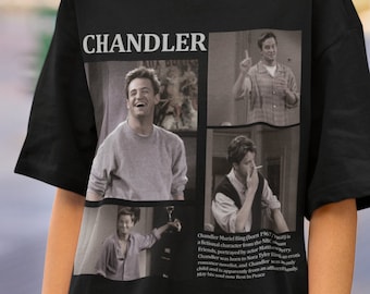 May include: Black t-shirt with a graphic print of Chandler Bing from the TV show "Friends". The graphic features four images of Chandler in different poses. The text "CHANDLER" is printed above the images. The text below the images reads "Chandler Muriel Bing (born 1967) is a fictional character from the NBC sitcom Friends, portrayed by actor Matthew Perry. Chandler was born to Nora Tyler and a romance novelist, and Chandler was an only child and is apparently from an affluent family. May his soul rest in peace."