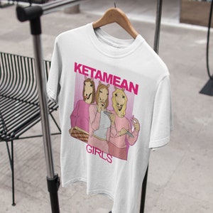 May include: White t-shirt with a pink graphic of three women with horse heads. The graphic says "KetameAn Girls".