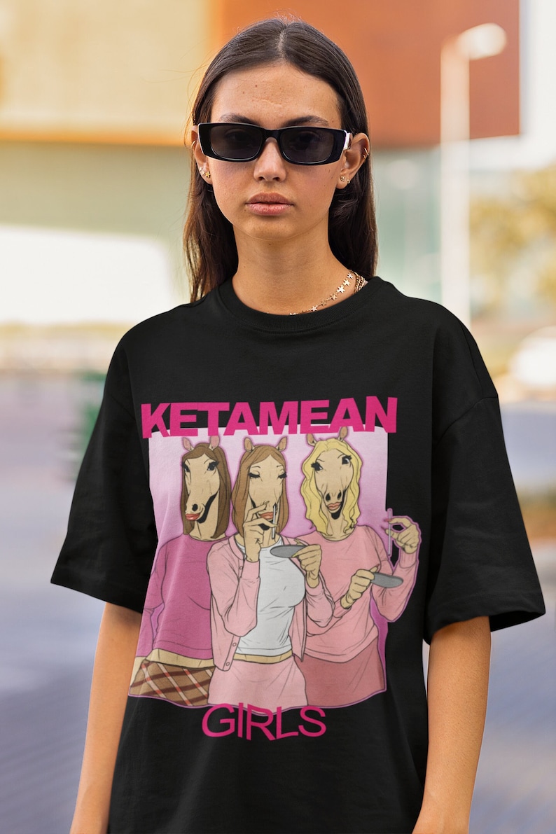 May include: Black t-shirt with a pink graphic of three women with horse heads. The graphic says "Ketamean Girls".