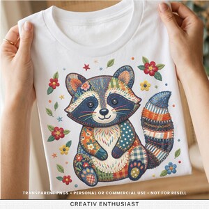 Könnte beinhalten: Weißes T-Shirt mit einem bunten Patchwork-Waschbär-Design. Der Waschbär hat ein blaues Gesicht, Knopfaugen und einen gestreiften Schwanz. Blumen- und Sternakzente umgeben den Waschbären. Der Text "TRANSPARENT PNGS • PERSONAL OR COMMERCIAL USE • NOT FOR RESELL" steht unten.