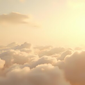 May include: A serene image of a cloudscape bathed in warm, golden light. Fluffy, textured clouds fill the lower portion of the frame, with a gradient of light transitioning to a bright, sunny sky above. The overall effect is soft and dreamy.