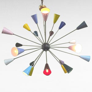 Może przedstawiać: Kolorowy żyrandol w stylu mid-century modern z wieloma stożkowymi kloszami w różnych kolorach, w tym różowym, żółtym, niebieskim i zielonym. Oprawy oświetleniowe rozmieszczone są wokół centralnej kuli.