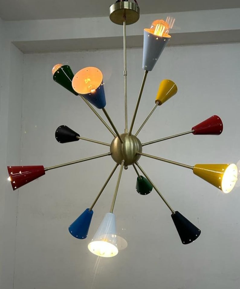 Może przedstawiać: Żyrandol w stylu mid-century modern z mosiężnym wykończeniem i wieloma stożkowymi kloszami w r&oacute;żnych kolorach, w tym czerwonym, ż&oacute;łtym, niebieskim, zielonym i czarnym. Oprawy oświetleniowe są podświetlone.