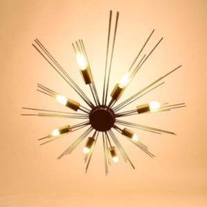 May include: A starburst ceiling light fitting with multiple bulbs. The fitting has a dark brown central hub with radiating rods and gold-coloured bulb holders. The bulbs are lit, emitting a warm glow. The design is modern and decorative, suitable for various interior styles.
