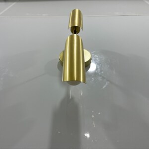 Pode incluir: Uma arandela de parede dourada com duas lumin&aacute;rias. A arandela tem um design simples e moderno.