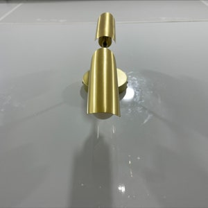 Pode incluir: Uma arandela de parede dourada com duas lumin&aacute;rias. A arandela tem um design simples e moderno.
