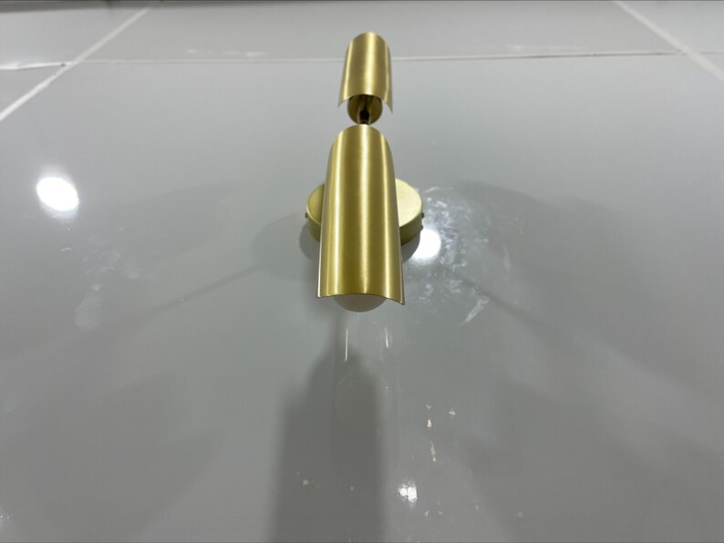 Pode incluir: Uma arandela de parede dourada com duas lumin&aacute;rias. A arandela tem um design simples e moderno.