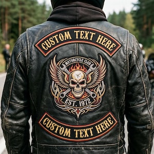 May include: A black leather motorcycle jacket featuring a large back patch with a central skull, wings, and crossed wrenches. The patch includes the text "MOTORCYCLE CLUB" and "EST. 1972". Two curved patches above and below read "CUSTOM TEXT HERE".