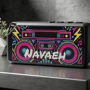 May include: A rectangular black Bluetooth speaker featuring a vibrant, colorful graphic print of a retro boombox on the front grille. The design includes bright pink speakers, yellow lightning bolts, and the name NAVAEH in white block letters.