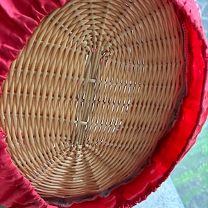 May include: The bottom of a wicker basket is covered with a red fabric lining. The fabric has a ruffled edge.