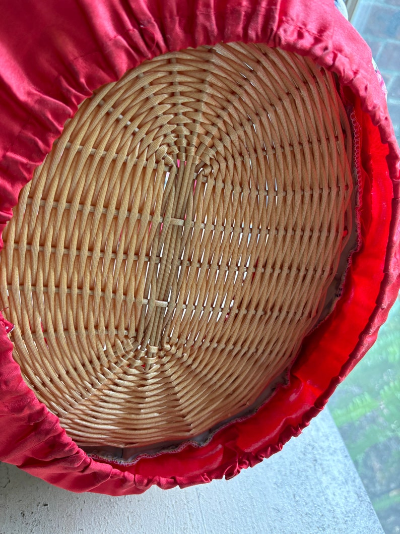 May include: The bottom of a wicker basket is covered with a red fabric lining. The fabric has a ruffled edge.